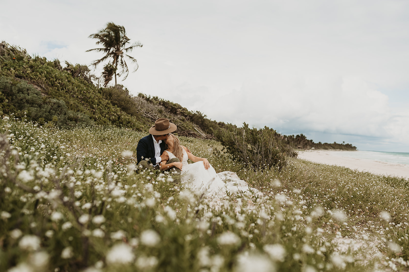 Tulum Destination Wedding - Couple sitting and kissing in a beach dune in Tulum, Mexico Sian Ka'an
